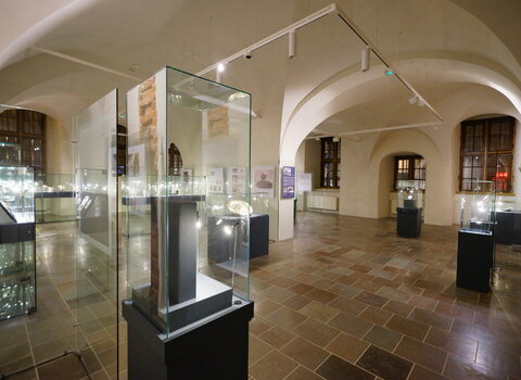 Zdjęcie przedstawia salę wystawową ze sklepieniami w kształcie łuku. W centrum gabloty z przedmiotami. 