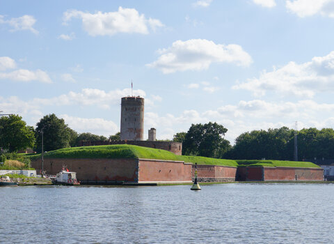 Zdjęcie przedstawia jeden z bastionów Twierdzy widoczny od strony otaczającego ją kanału wodnego. W tle widoczna wieża.