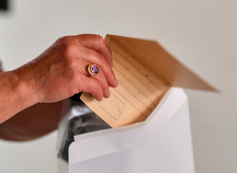 Zdjęcie przedstawia dłonie trzymające zgięty w połowie list. 