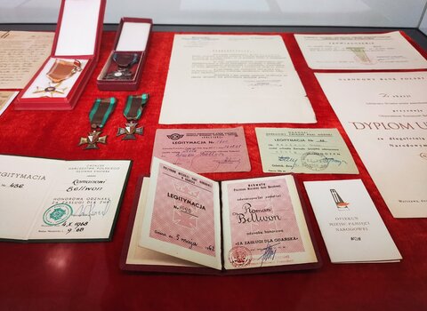 Zdjęcie przedstawia rozłożone na stole pamiątki, liczne odznaczenia, medale oraz dokumenty i legitymacje.