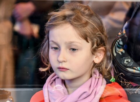 Zdjęcie. Dziewczynka ogląda biżuterię z bursztynu bałtyckiego.  