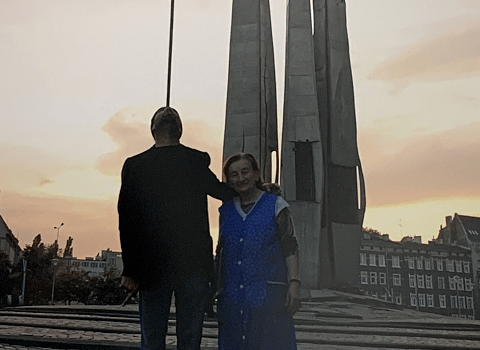 Zdjęcie. Chłopiec ogląda wielkoformatowe zdjęcie dwóch osób stojących prze Pomnikiem Poległych Stoczniowców 1970.