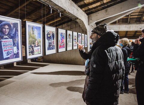 Zdjęcie. Sale gdańskiej Galerii Sztuki WL4. Na sali wiszą zdjęcia oglądane przez zwiedzających odzianych w czapki i zimowe kurtki. 
