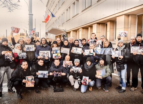 Zdjęcie wspólne fotoreporterów wraz ze zdjęciami prezentowanymi podczas żałoby na tle Urzędu Miejskiego w Gdańsku. 