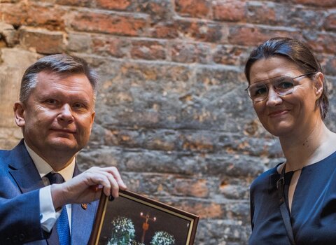 Zdjęcie. Waldemar Ossowski (z lewej) prezentuje wraz z Karoliną Misztal (z prawej) przekazane do zbiorów Muzeum Gdańska zdjęcie. 