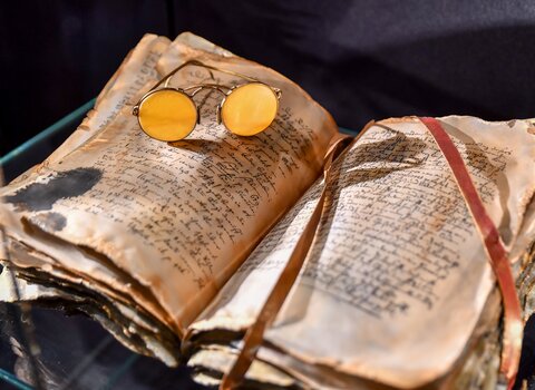 Zdjęcie. Okulary z bursztynowymi soczewkami położone na książce.   