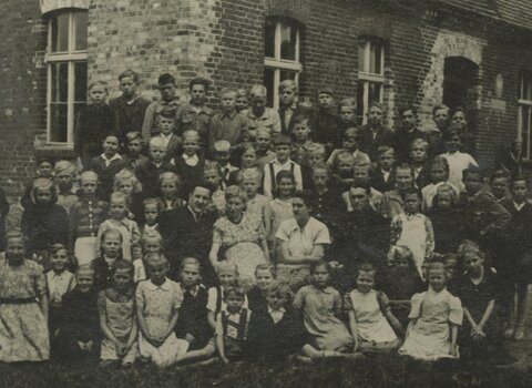 Uczniowie i nauczyciele przed szkołą w Kokoszkach. Zdjęcie czarno-białe. 