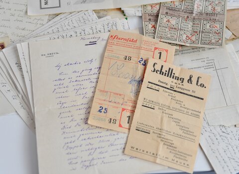 Dokumenty, ulotki z zakładu optycznego i bilety z okresu 1919-1939. Po lewej list w języku niemieckim. Rozpoczęcie listu to zawołanie w języku polskim "Mój skarbie złoty!"  