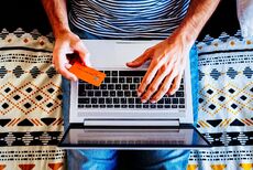 Large_MS PPT_Web-Overhead view of man sitting with his laptop on his lap and his bank card in his hand.jpg