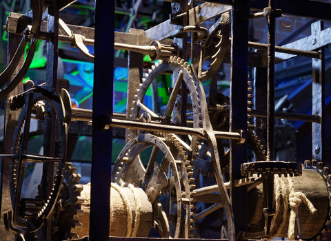 Zdjęcie przedstawia mechanizm starego zegara wieżowego. Zbliżenie na koła zębate i przekładki. 