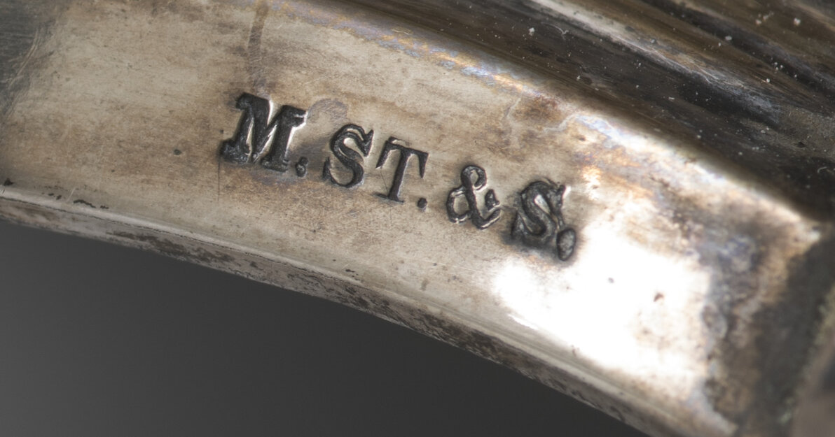 Zdjęcie przedstawia srebrny element z wybitą inskrypcją "M. ST. & S" od Mortiz Stumpf & Sohn (Maurycy Stumpf i Syn)