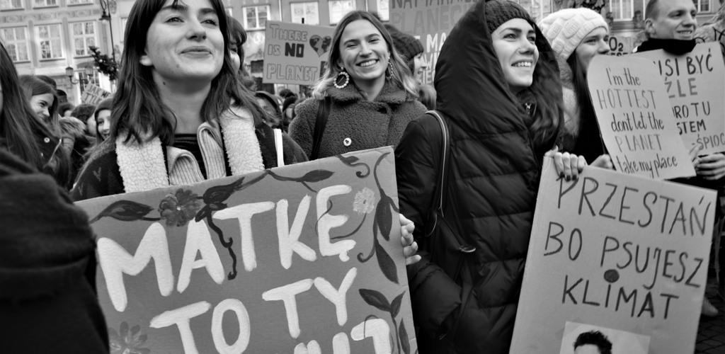Czarno-białe zdjęcie. Kobiety na Długim Targu w Gdańsku. Trzymają transparenty z napisami. Na pierwszym planie kobieta z napisem: "Matkę to ty szanuj". 