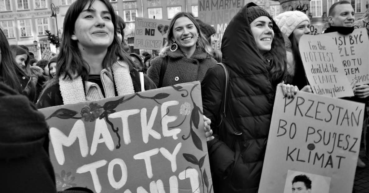 Czarno-białe zdjęcie. Kobiety na Długim Targu w Gdańsku. Trzymają transparenty z napisami. Na pierwszym planie kobieta z napisem: "Matkę to ty szanuj". 